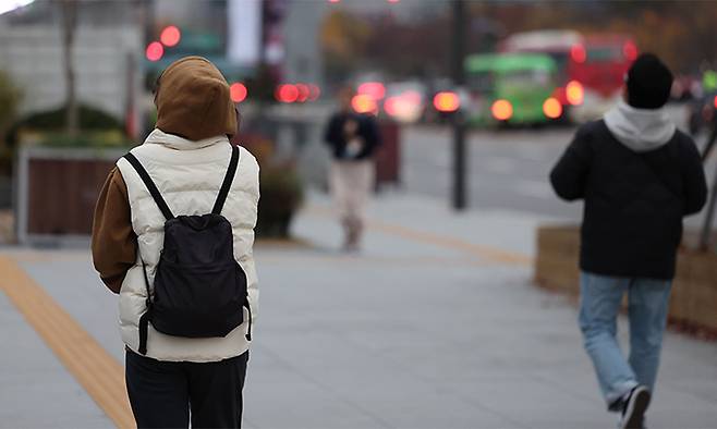 가을비가 내린 뒤 쌀쌀한 날씨를 보이는 지난 13일 서울 광화문광장에서 두툼한 옷을 입은 시민들이 길을 걷고 있다. 연합뉴스