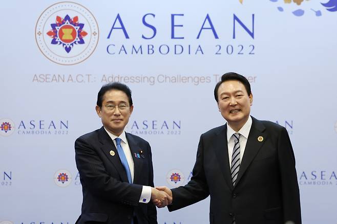 President Yoon Suk-yeol shakes hands with Japanese Prime Minister Fumio Kishida and takes a commemorative photo at the Korea-Japan summit held at a hotel in Phnom Penh, Cambodia on Sunday. (Yonhap)