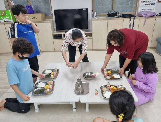 아현1동경로당 돌봄교실에서 자원봉사 주민이 돌봄교실 아동의 저녁식사를 챙겨주고 있다. [마포구 제공]