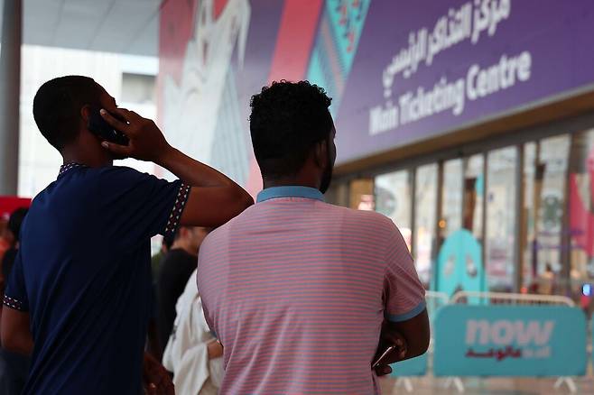 한 시민이 지난 17일 카타르 도하 주 매표소 들머리 전광판을 살펴보다 전화로 현재 상황을 지인에게 통화로 알리고 있다. 도하/김혜윤 기자