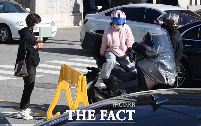 한 수험생이 어머니가 지켜보는 가운데, 퀵서비스 오토바이에 탑승하고 있다.
