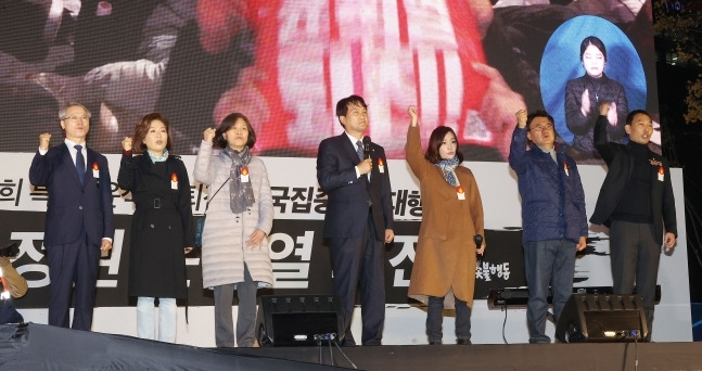 19일 오후 서울 중구 숭례문 인근에서 촛불전환행동 주최로 열린 윤석열 정부의 퇴진을 요구하는 촛불집회에서 더불어민주당 안민석 의원(가운데)이 발언하던 중 다른 의원들이 손을 들어올려 보이고 있다. 왼쪽부터 무소속 민형배 의원, 더불어민주당 양이원영 의원, 강민정 의원, 안민석 의원, 유정주 의원, 황운하 의원, 김용민 의원.[사진출처=연합뉴스]