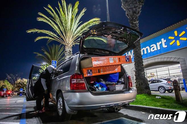 추수감사절 다음날 새벽 미국 캘리포니아주 남부 도시 토렌스 소재 월마트 매장 앞에서 한 남성이 구입한 물품들을 자동차에 싣고 있다. 2021. 11.26 ⓒ AFP=뉴스1
