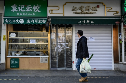 중국 수도 베이징에서 마스크를 쓴 시민이 최근 코로나19 확산으로 문을 닫은 차오양구의 한 음식점 앞을 지나고 있다. AFP연합뉴스