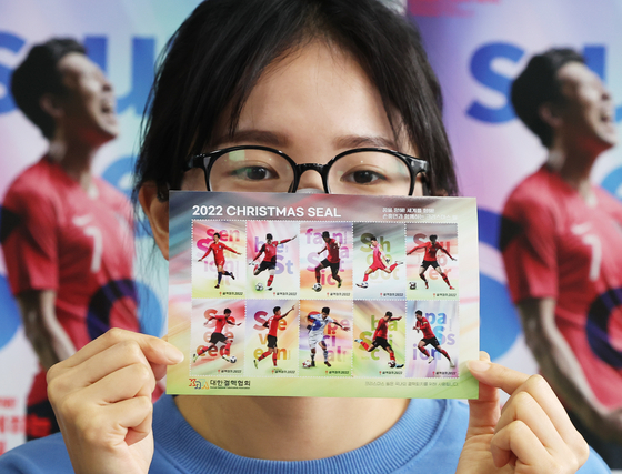 An employee at the Korean National Tuberculosis Association's Gyeonggi office in Suwon shows Christmas stamps on Tuesday. This year's Christmas stamps feature Korea's football star Son Heung-min. [YONHAP]