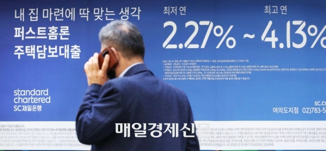 한 시민이 시중은행 대출 안내문 앞을 지나가고 있다. [사진 = 한주형 기자]