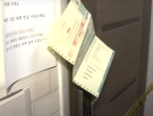 23일 서울 서대문구의 한 다세대주택에서 숨진 모녀의 원룸 현관문. 집주인의 통보와 연체된 전기 요금서가 붙어있다. /연합뉴스TV 유튜브 캡처