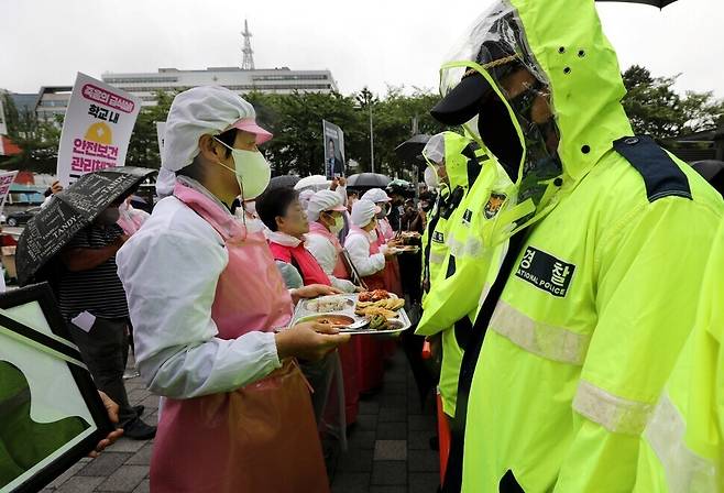 민주노총 전국학교비정규직노동조합 조합원들이 지난 6월15일 서울 용산 대통령실 주변 도로에서 안전하고 건강한 학교급식 운영을 촉구하는 기자회견을 한 뒤, 음식이 담긴 식판을 든 채 행진하다 경찰에 가로막혔다. 이들 머리 위로 국방부 청사가 보인다. 대통령 집무실이 있는 건물은 국방부 뒤편에 있어 보이지 않는다. 이들은 폐암으로 산업재해 인정을 받고 숨진 학교급식 노동자 5명을 추모하며, 급식조리실 환기시설 개선 등 대책 마련을 호소했다. 류우종 기자 wjryu@hani.co.kr
