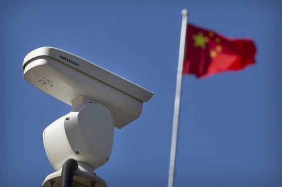 중국 수도 베이징의 한 교차로에 설치된 감시 카메라 너머로 중국 홍성홍기가 휘날리고 있다. 미국은 2019년 10월 중국의 한 테크기업에 대해 이 기업의 인공지능 기술이 중국 내 무슬림 소수민족을 감시하는 데 쓰이고 있다며 제재를 가했다. [AP=연합뉴스]