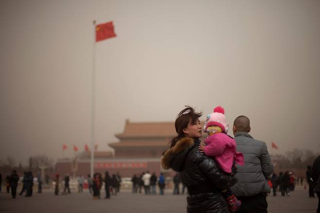 스모그에 황사까지 겹치면서 ‘엄중 수준’의 대기오염 경보가 발령된 중국 수도 베이징의 톈안먼 광장에서 28일 한 여성이 마스크를 쓴 아기를 안고 있다.  AP 연합뉴스