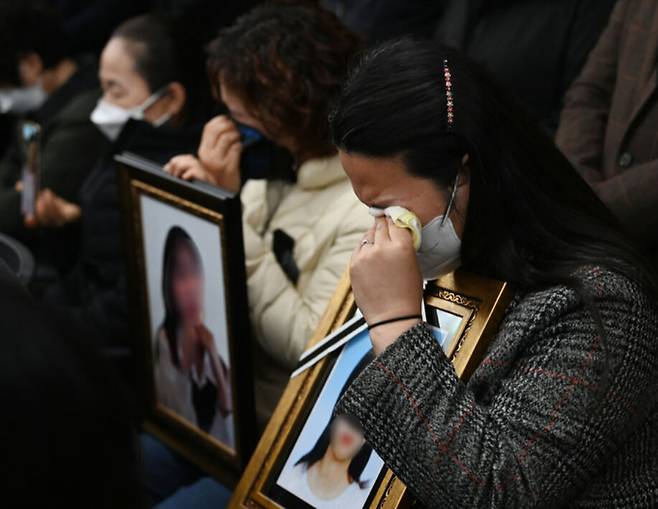 이태원 참사 유가족들이 지난 22일 서울 서초구 민주사회를 위한 변호사모임(민변)에서 열린 입장발표 기자회견에서 희생자들의 사진을 들고 눈물을 닦아내고 있다. 연합뉴스