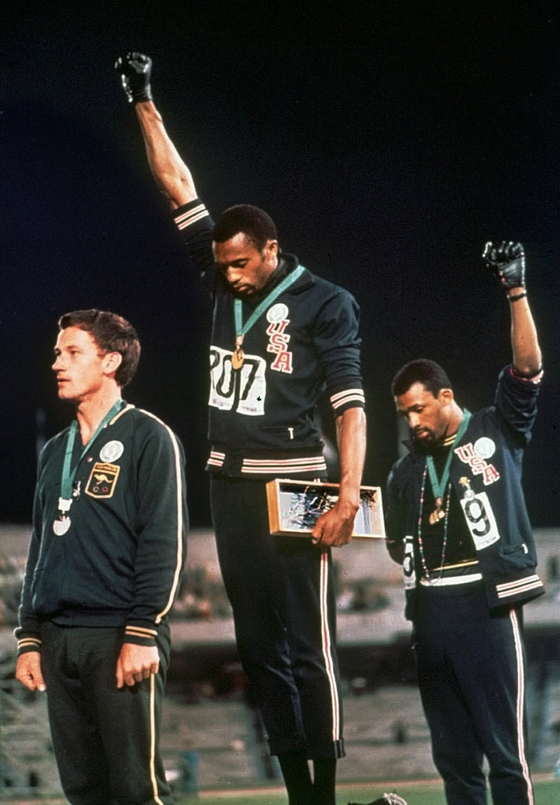 1968년 멕시코 올림픽 육상 200m 우승자 토미 스미스(미국·사진 가운데)가 인종차별에 항의하며 검은 장갑을 낀 오른손을 들고 있다. [중앙포토]