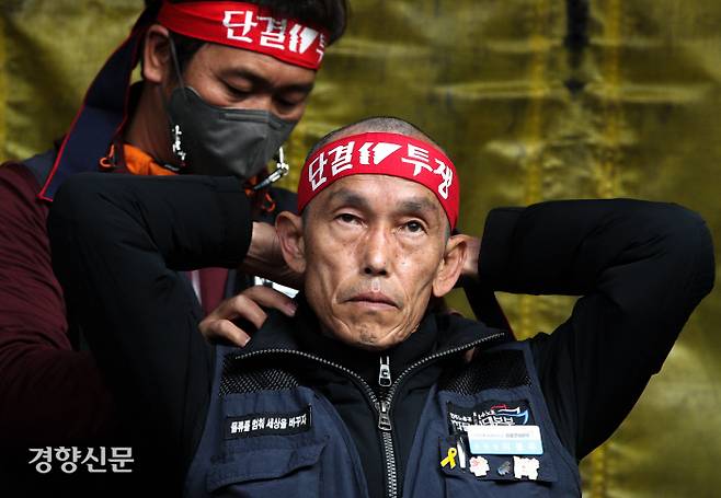 삭발 뒤 머리띠 묶고 이봉주 화물연대 위원장이 29일 오후 경기 의왕시 내륙컨테이너기지(ICD) 인근에서 열린 총파업 결의대회에서 업무개시명령에 반발하는 삭발식을 가진 뒤 머리띠를 묶고 있다. 성동훈 기자