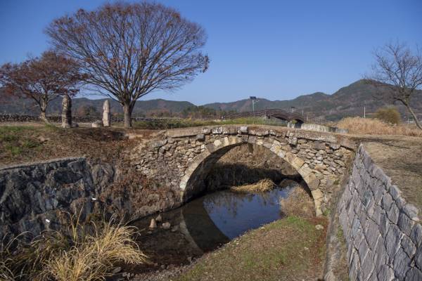 아래 중앙에 용머리로 장식된 홍교와 그 왼쪽에 서 있는 석장승.