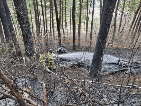 27일 오후 소방관들이 강원 양양군 현북면 어성전리 명주사 인근 숲속에 추락한 산불진화용 민간업체 임차 헬리콥터 사고 현장에서 잔불을 끄기 위해 물을 뿌리고 있다. (사진=양양군청 제공) 2022.11.27. [사진=뉴시스 ]