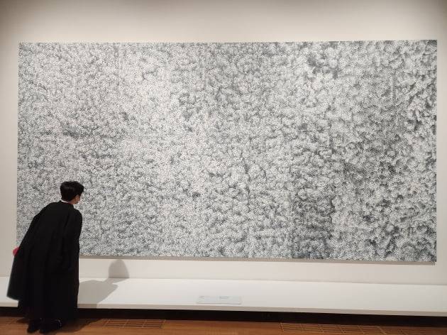 한 관람객이 쿠사마의 2007년작 'Infinity-nets(QQABT)'을 감상하고 있다. 이 '무한망 시리즈'는 서구 수집가들 사이에서 가장 인기 있는 시리즈로 꼽힌다. 50여년 전 작품에 비해 기법이나 완성도 측면에서 확연히 발전했다. 아래는 세부 확대.