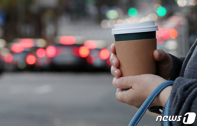 횡단보도에서 한 시민이 따뜻한 음료에 언 손을 녹이며 신호를 기다리고 있다. /뉴스1 ⓒ News1