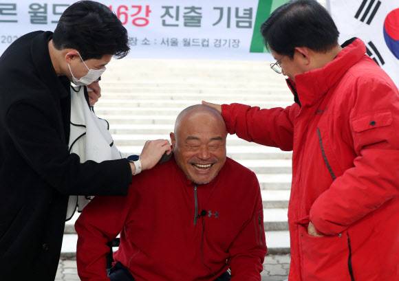 [서울=뉴시스]   박강수 마포구청장이 4일 오후 서울 마포구 서울월드컵경기장 앞에서 한국의 카타르 월드컵 16강 진출시 삭발 공약을 지킨 방송인 김흥국의 머리를 만지고 있다. 2022.12.04.