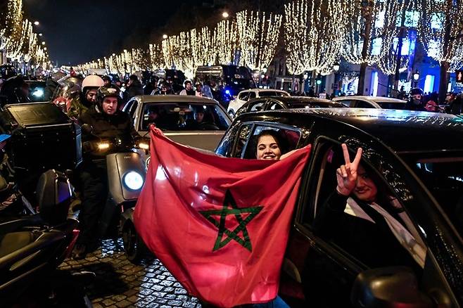 6일(현지시간) 축구 국가대표팀이 카타르 월드컵 16강 스페인전에서 승리하자 모로코 축구팬들이 프랑스 수도 파리의 샹젤리제 거리에서 국기를 흔들며 환호하고 있다. 파리=AFP연합