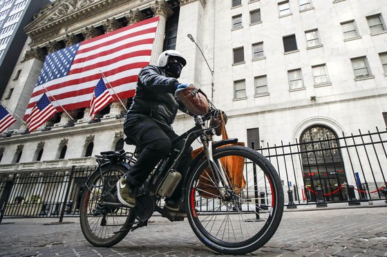 배달원이 뉴욕의 증권 거래소를 지나 전기 자전거를 타고 있다. AP=연합뉴스