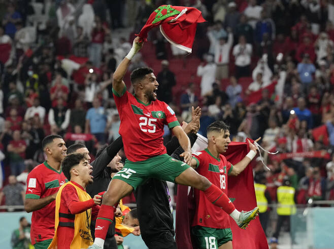 공은 둥글다! 모로코 축구대표팀 선수들이 11일 카타르 도하 앗수마마 스타디움에서 포르투갈과 맞선 2022 카타르 월드컵 8강전에서 1-0으로 이겨 4강에 진출하게 되자 국기를 들고 환호하고 있다. 도하 | AP연합뉴스