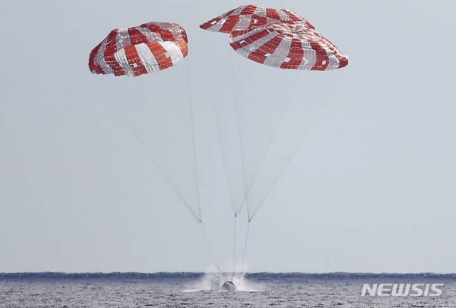 [워싱턴=AP/뉴시스] 미국 항공우주국(NASA)의 우주선 아르테미스 1호의 무인 캡슐 '오리온'이 11일(현지시간) 달 여행을 마치고 지구로 귀환해 멕시코 인근 태평양으로 착수하고 있다. 지난달 16일 플로리다주 케네디 우주센터에서 발사된 오리온은 25일 동안의 임무를 마치고 무사히 귀환했다. 2022.12.12.