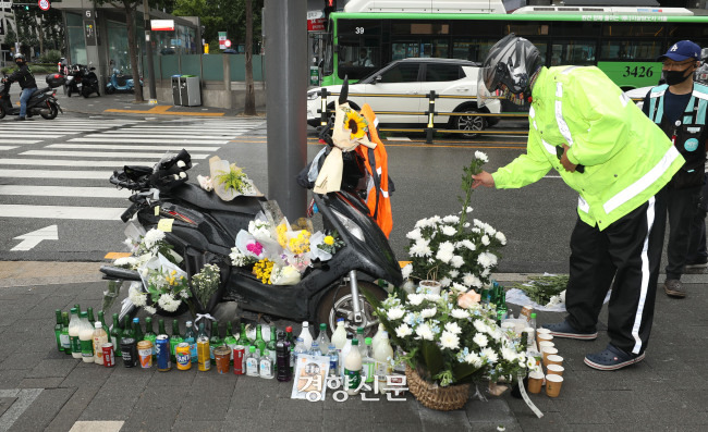 한 배달노동자가 2021년 8월 27일 서울 강남구 선릉역에서 전날 화물차에 치어 숨진 오토바이 배달노동자를 추모하고 있다. /강윤중 기자