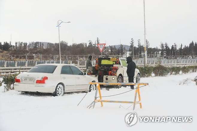 폭설에 구난·견인되는 차량 (제주=연합뉴스) 박지호 기자 = 대설특보가 내려진 18일 제주시 애월읍 평화로에서 한 승용차가 구난 견인되고 있다. 2022.12.18 jihopark@yna.co.kr