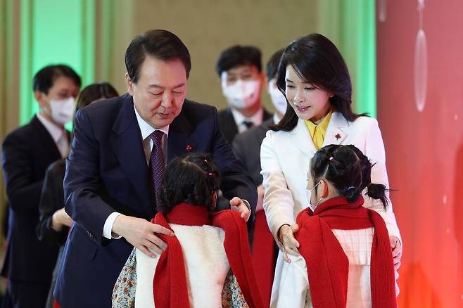 윤석열 대통령과 부인 김건희 여사가 23일 청와대 영빈관에서 열린 보호아동·자립준비청년과 함께하는 크리스마스 행사에서 아이들에게 목도리를 걸어주고 있다.  【사진 제공=대통령실】