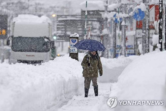 폭설 내린일본 니가타현 우오누마 (우오누마[일본] AP·교도=연합뉴스) 20일 한 시민이 눈이 높게 쌓인 일본 니가타현 우오누마의 거리를 걷고 있다. 2022.12.21 clynnkim@yna.co.kr