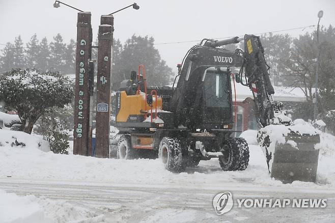 눈 치우는 굴삭기 (제주=연합뉴스) 박지호 기자 = 제주도 전역에 폭설이 내린 23일 오후 제주시 조천읍 교래리의 한 식당 입구에서 굴삭기가 쌓인 눈을 치우고 있다. 2022.12.23 jihopark@yna.co.kr