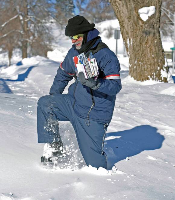 23일(현지시간) 미 노스다코타주 맨던에서 한 집배원이 영하 30도의 날씨 속 무릎까지 쌓인 눈을 헤치며 우편물을 배달하고 있다. [사진=뉴시스]