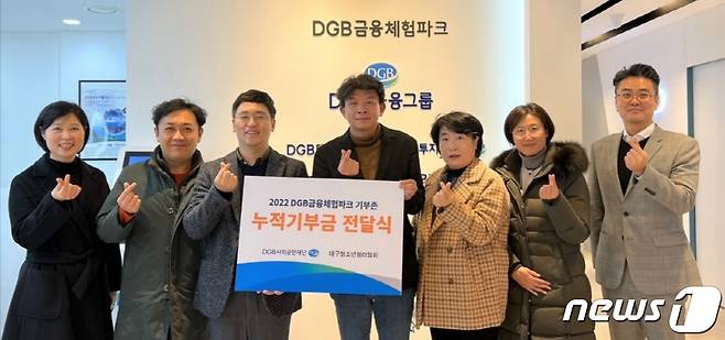 DGB사회공헌재단 직원들이 '2022 금융체험파크 기부존 누적기부금'을 대구청소년쉼터협회에 전달한 뒤 손가락 하트를 만들어 보이고 있다.(대구은행 제공)