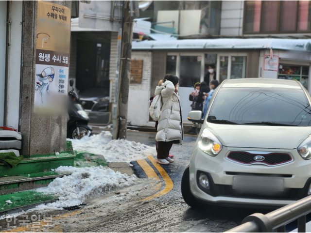 21일 서울 성북구 장위초 정문 앞 사거리에서 한 어린이가 보행로가 없는 차도 위에 서서 차량이 지나가길 기다리고 있다. 이서현 기자