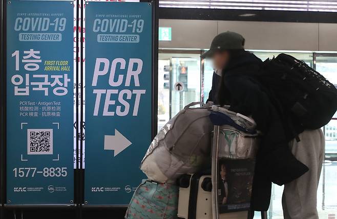 김포공항 국제선 입국장 내 PCR 검사장 안내판 앞을 지나는 해외 입국자 모습. /뉴스1