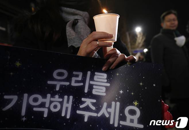 16일 저녁 서울 용산구 이태원역 앞에서 열린 '10.29 이태원 참사 49일 시민추모제'에서 참석자들이 '우리를 기억해 주세요' 손피켓을 들고 있다. 2022.12.16/뉴스1 ⓒ News1 송원영 기자