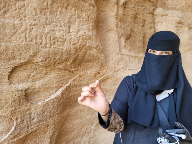 자발 이틀립의 벽면에는 다양한 문양과 글씨가 기록돼 있다. 하트모양의 문양 앞에 선 사우디 여인.