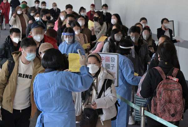 푸른색 방역복을 입은 인천국제공항 관계자들이 2일 공항 제1여객터미널 입국장으로 들어오는 승객 중 중국발 입국자를 분류해 관련 서류 제출을 안내하고 있다. 정부는 이날부터 중국에서 출발한 입국자 전원에 대해 코로나19 유전자증폭(PCR) 검사를 의무 실시하고 결과가 나올 때까지 격리하도록 했다. 인천=권현구 기자