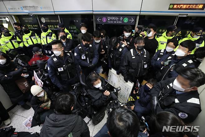 [서울=뉴시스] 조수정 기자 = 지난 3일 오전 서울 지하철 4호선 동대문역사문화공원역 승강장에서 전국장애인차별철폐연대(전장연) 회원들이 254일차 장애인 권리예산 입법 쟁취 지하철 선전전을 위해 탑승하려던 중 저지하는 서울지하철공사 직원 및 경찰들에게 가로막혀 있다. 전장연은 이날 4호선 성신여대입구 역에서 탑승했다가 동대문역사문화공원 역에서 하차했다. 다시 탑승하고 삼각지역으로 향해 집회를 이어가려고 했으나 교통공사와 경찰의 탑승 저지로 이동하지 못하고 있다. 2023.01.04. chocrystal@newsis.com