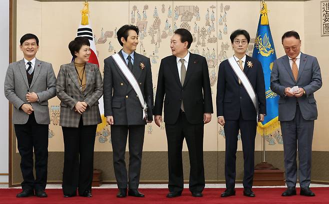 윤석열 대통령이 지난달 27일 서울 용산 대통령실 청사에서 '오징어게임'으로 미국 에미상 남우주연상을 받은 배우 이정재(왼쪽 세번째), 황동혁 감독(오른쪽 두번째)에게 금관문화훈장을 수여한 뒤 기념촬영을 하고 있다./연합뉴스