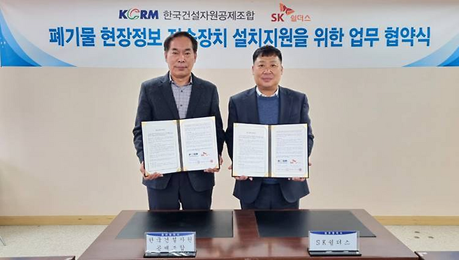 지난 5일 SK쉴더스와 한국건설자원공제조합이 폐기물 현장정보 전송장치 설치지원을 위한 업무협약을 체결했다. SK쉴더스 이왕장 전략영업그룹장(사진 오른쪽)과 한국건설자원공제조합 이영성 전무이사가 사진 촬영을 하고 있다. <사진제공=SK쉴더스>