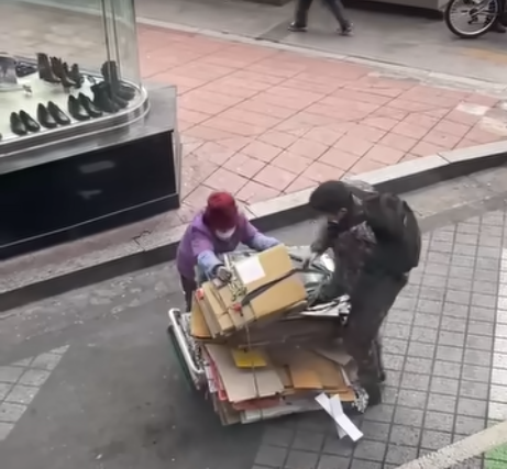 서울 영등포에서 한 군인이 폐지 모으는 할머니의 수레에 쌓인 폐지가 무너지려 하자 돕는 모습. '육군훈련소 대신 전해드립니다' 페이스북 캡쳐.