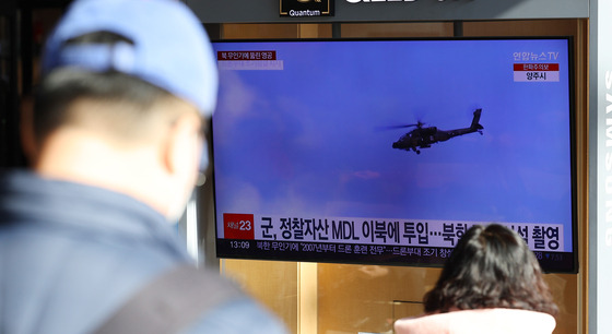 Passersby watch a televised news about possible North Korean drones crossing the border at Seoul Station on Tuesday. [YONHAP]