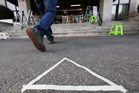 Tape marks the spot where Democratic Party leader Lee Jae-myung will be questioned by reporters before entering the Suwon Prosecutors’ Office in Seongnam, Gyeonggi, on Tuesday. Lee is being investigated over a corporate sponsorship of a Seongnam soccer club when he served as the city’s mayor. Prosecutors say that the 16 billion won sponsorship from companies including Doosan and Naver was a quid pro quo for favors received. [YONHAP]