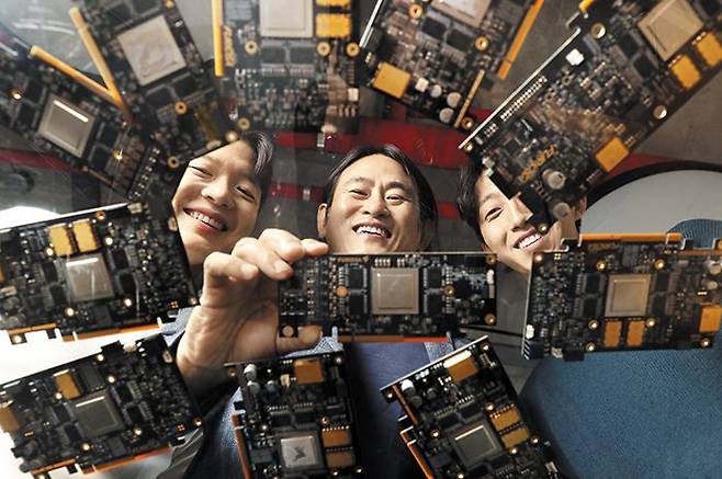 퓨리오사의 반도체 ‘워보이’ - 지난달 28일 서울 강남구에 있는 반도체 설계 스타트업 퓨리오사AI 연구실에서 백준호(가운데) 대표와 직원들이 자사 AI(인공지능) 전용 반도체 ‘워보이’가 장착된 기판을 바라보며 웃고 있는 모습. 워보이는 퓨리오사AI가 세계시장을 겨냥, 약 6년에 걸쳐 독자 개발한 것이다. /오종찬 기자