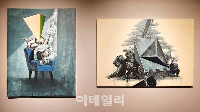 조문기의 ‘추락하는 자식을 삼키는 남자’(2020·145.5×112㎝·왼쪽)와 ‘대부님 기계장치를 타고 내려오신다’(2020·112.3×162.2㎝). 작가는 “가부장적 가족관이 충돌하는 소재를 다룬 시리즈”라고 전시작을 소개했다. 자칫 ‘험악하게’ 보이는 장면을 두곤 “미디어를 통해 굴절된 인간 군상들을 바라보다가 현실의 모양과 비교해 관찰했던 기억을 조합이 아닐까” 했다(사진=오현주 문화전문기자).