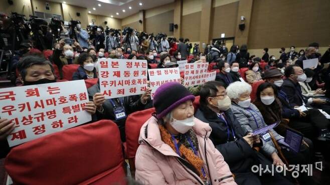 12일 국회에서 열린 강제징용 해법 논의를 위한 공개토론회에 참석한 참가자들이 피켓을 들고 있다./윤동주 기자 doso7@