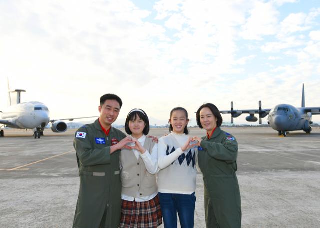 공군 최초 비행대대장 부부인 김익규·김민지 중령이 대대장으로서 지휘하는 E-737 항공통제기(왼쪽)와 C-130 수송기(오른쪽)를 배경으로 부부의 쌍둥이 자녀 영설, 은설양과 함께 하트를 만들어 보이고 있다. 사진은 왼쪽부터 김익규 중령, 은설양, 영설양, 김민지 중령. 공군 제공