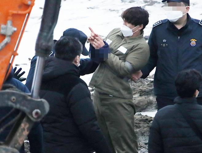 택시기사와 동거녀를 살해한 혐의로 구속된 이기영이 1월6일 오후 경기도 파주 공릉천변에서 검찰 관계자들에게 시신을 매장했다고 진술한 부근을 손으로 가리키고 있다. ⓒ 연합뉴스