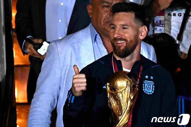 리오넬 메시가 20일(현지시간) 아르헨티나 부에노스아이레스 에세이사 국제공항에서 36년 만에 차지한 월드컵을 들고 전용기를 내리고 있다. ⓒ AFP=뉴스1 ⓒ News1 우동명 기자